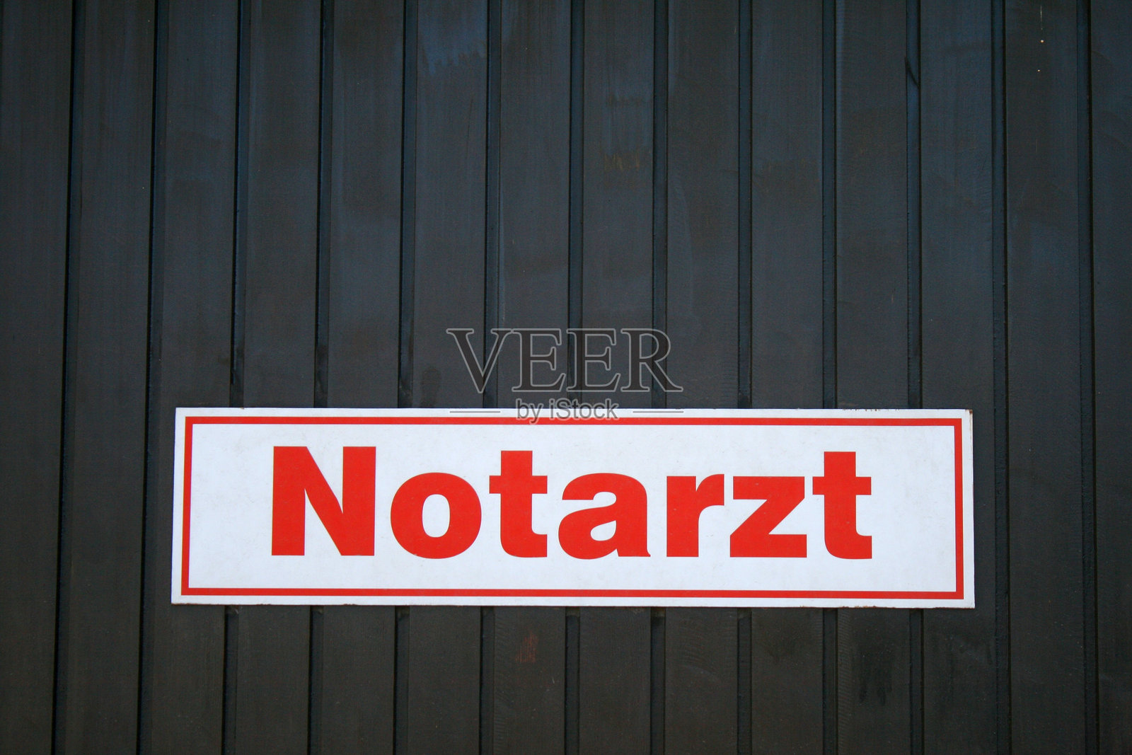 红色字母在白色背景上:“急救医生”(德语:“Notarzt”)标志贴在木墙上。照片摄影图片