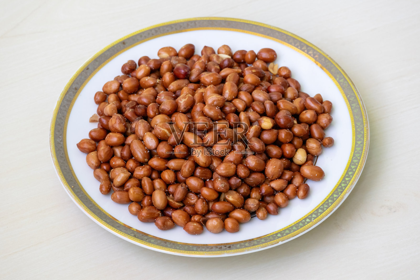 白色盘子里的香辣烤花生,放在木质表面上。照片摄影图片