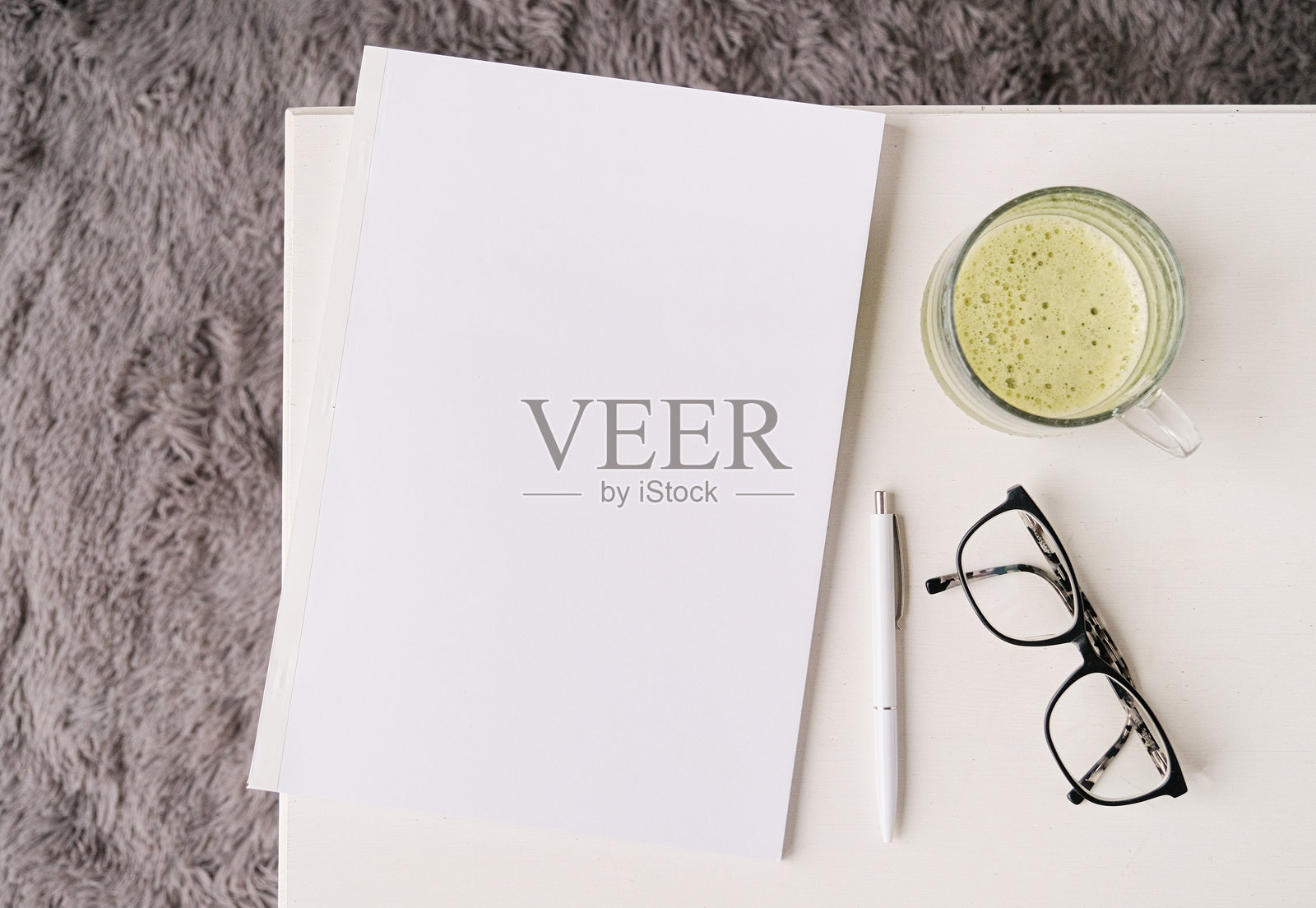 咖啡桌上的空白杂志模型,旁边有绿茶抹茶,窗边光线明亮。照片摄影图片