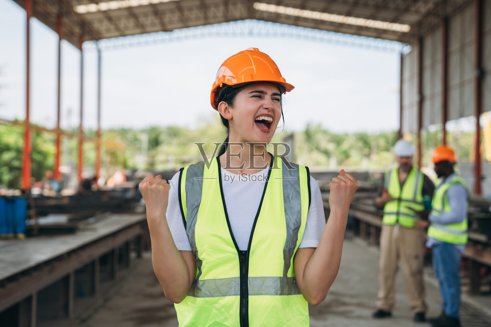 一位穿着黄色背心的女性微笑着,双手举向空中。照片摄影图片