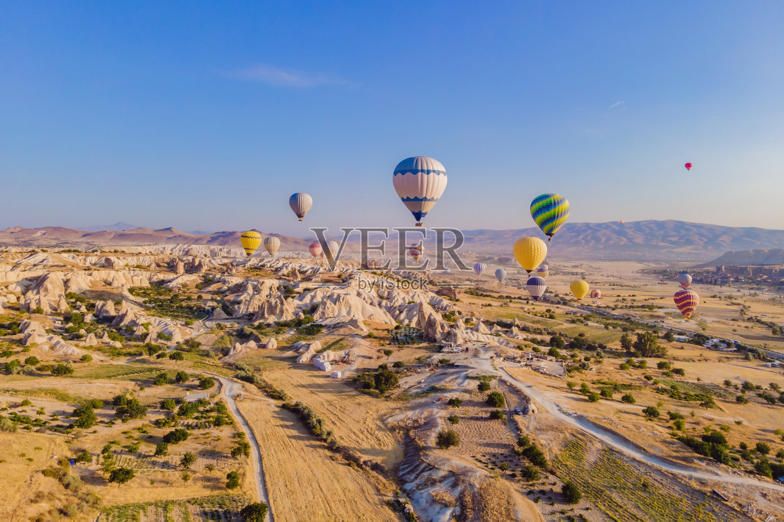 五彩缤纷的热气球飞越土耳其卡帕多奇亚的仙女烟囱谷。壮观的全景无人机视角展示了地下城市和热气球旅游。高质量。照片摄影图片