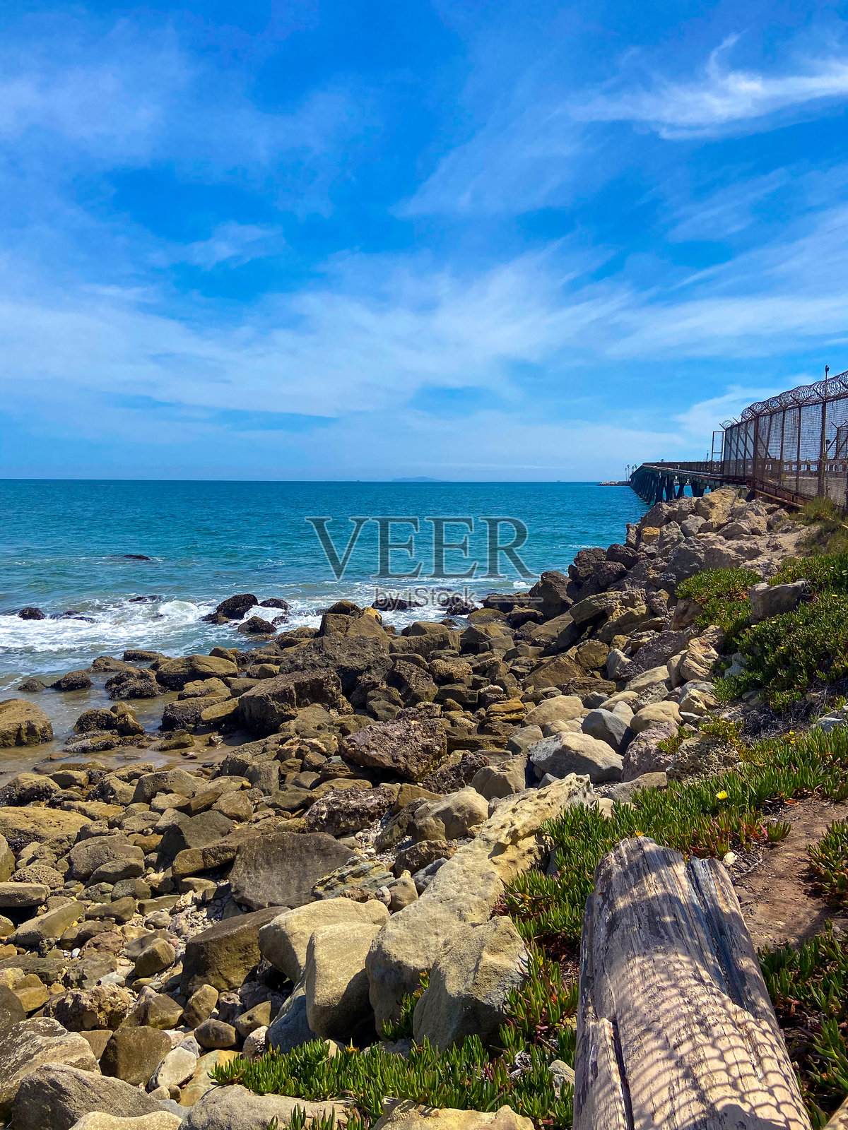 阳光明媚的日子里,蓝天白云下的码头附近岩石海岸照片摄影图片