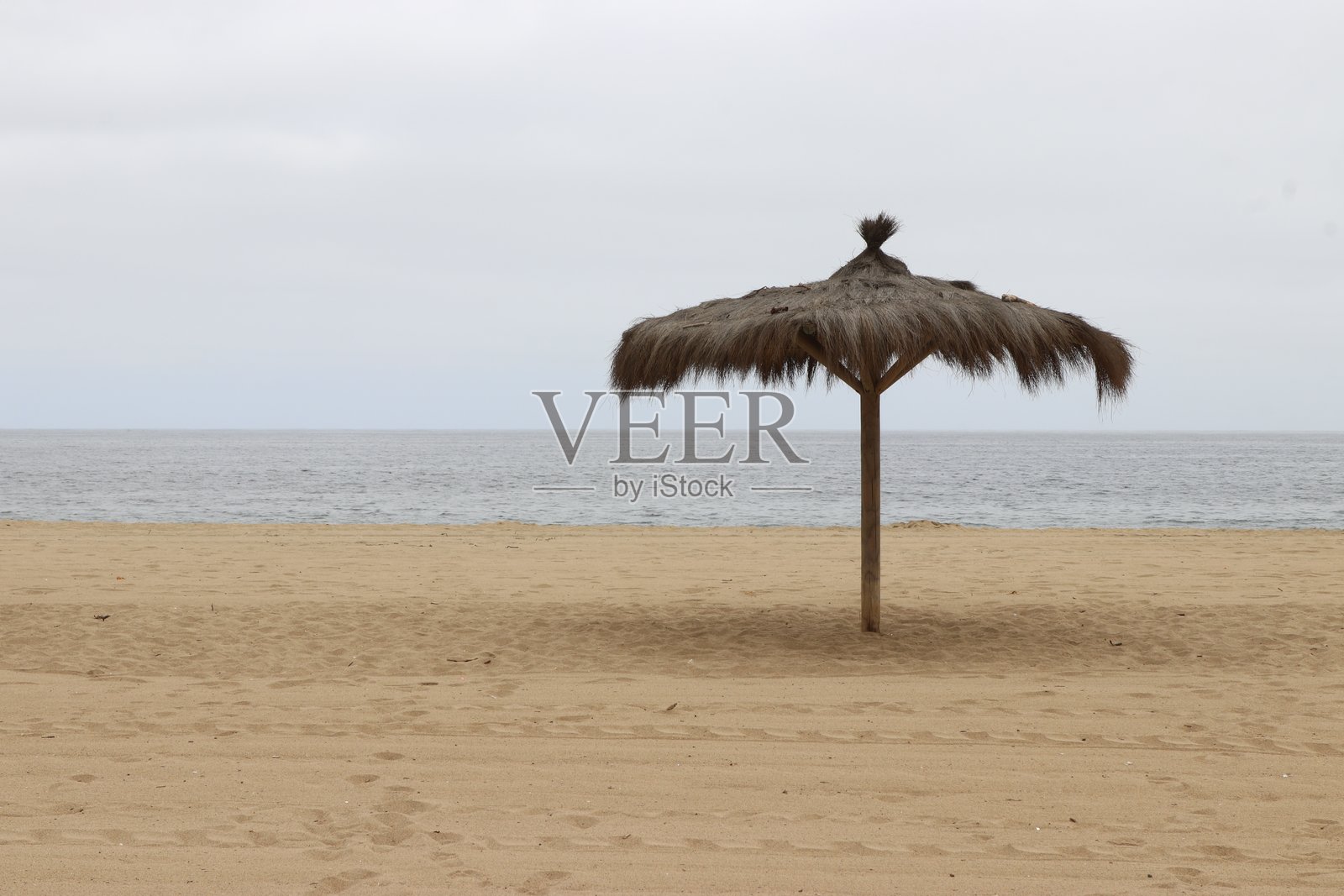 孤独海滩上的草伞照片摄影图片