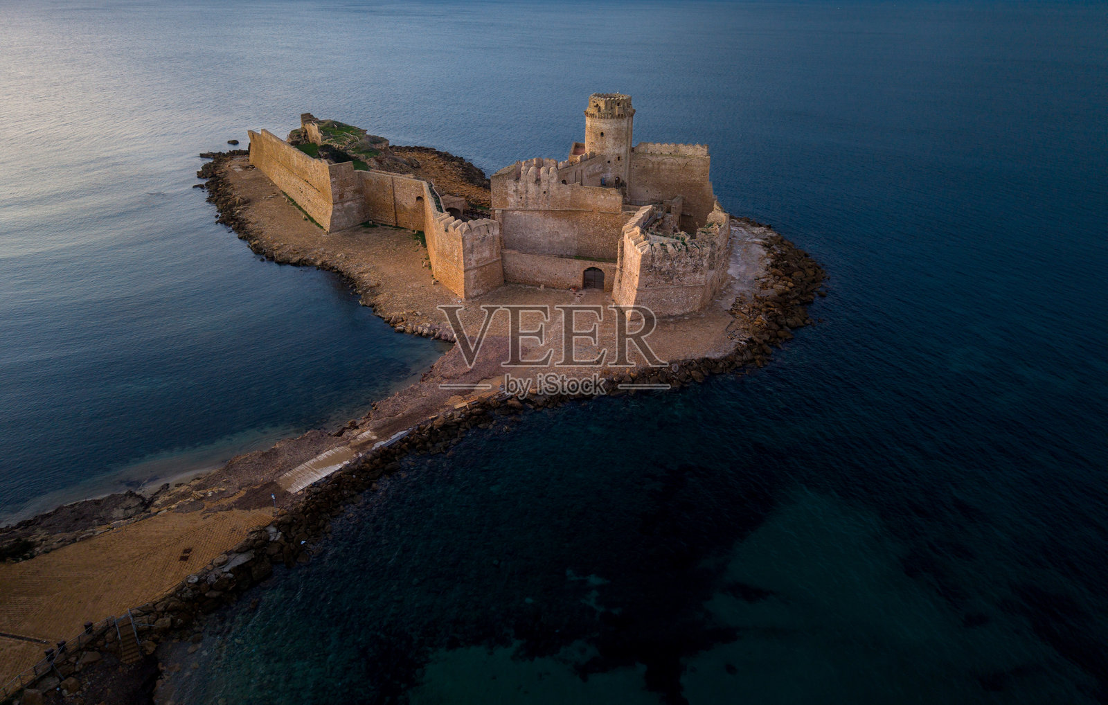 海边岛屿上的历史城堡遗址,傍晚的柔和光线映照着宁静的海水照片摄影图片