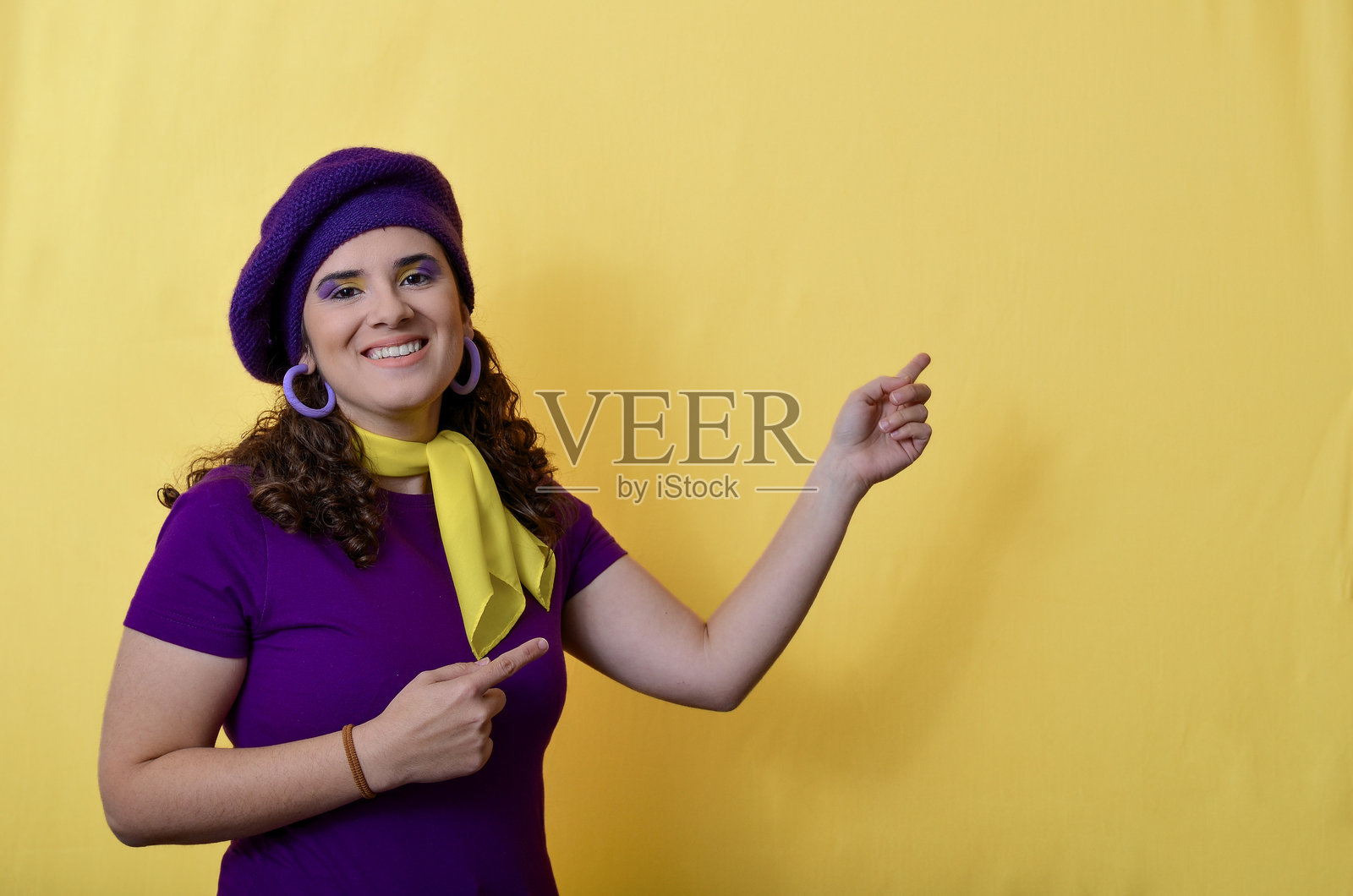 年轻女性在黄色背景下指向旁边和下方照片摄影图片