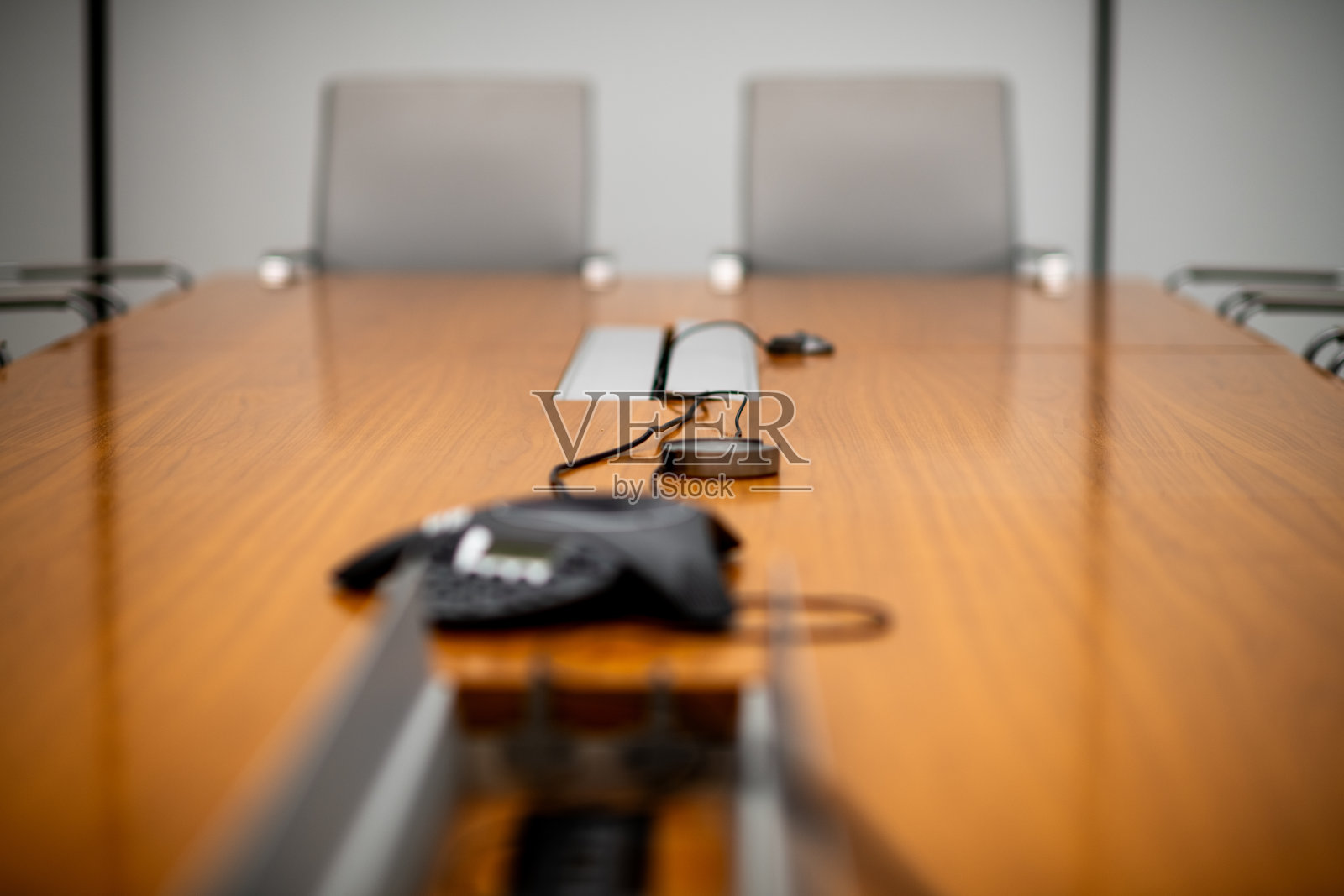 模糊的木质会议桌头部,配有灰色椅子和电话扬声器照片摄影图片