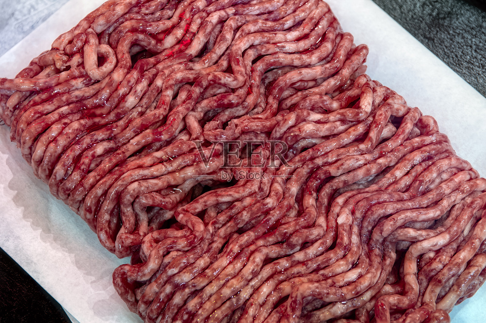 新鲜生绞肉放在纸上,猪肉、牛肉、肉馅特写,孤立在白色背景上,俯视图。照片摄影图片