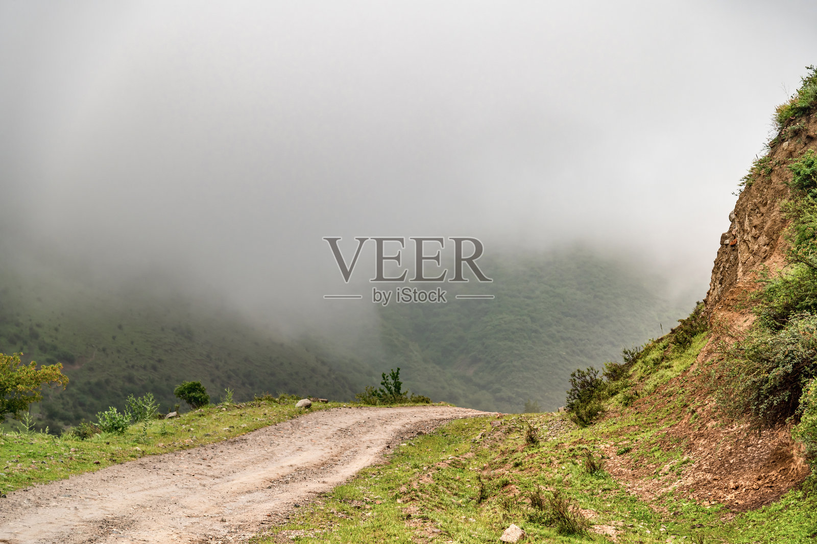 雨后山路。灰色雾霭的天空和湿滑的山路。照片摄影图片