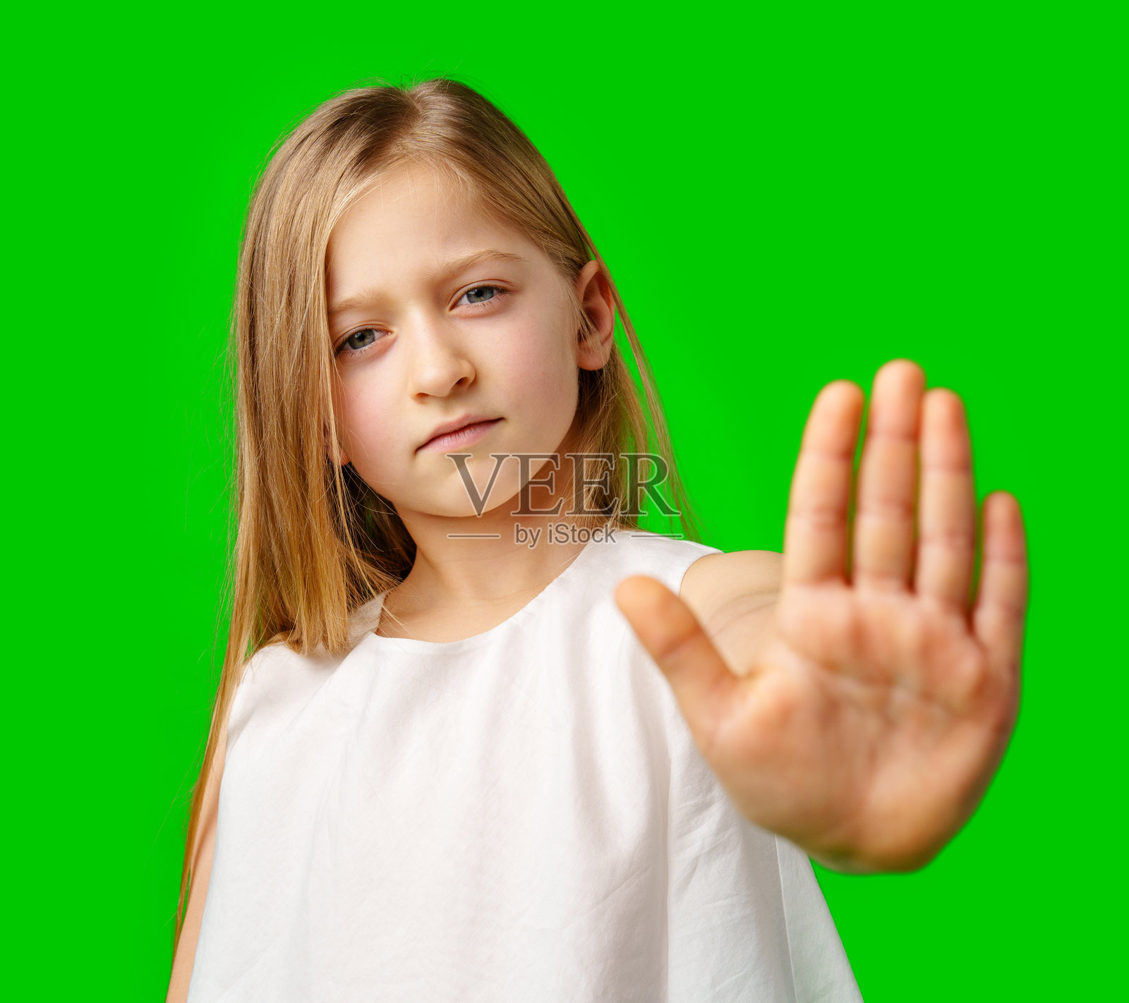 长发女孩在绿色背景前举手做出停止的手势照片摄影图片