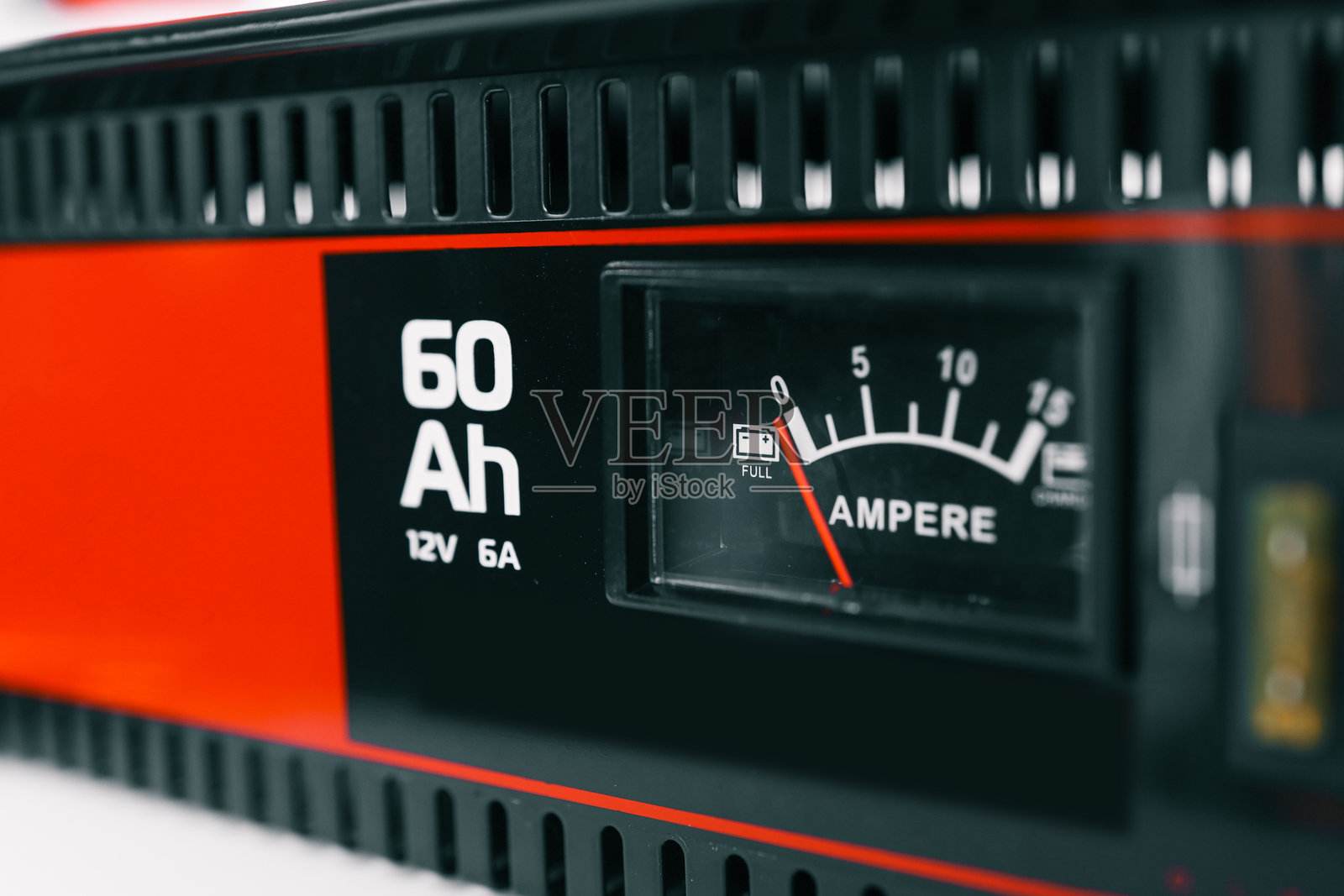 电池充电器的特写,带有安培表和显示60安时的容量指示器。红色指针指向黑色和红色设备上的满电状态。照片摄影图片