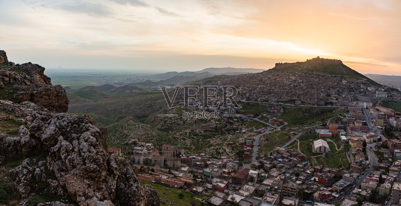 马尔丁城堡矗立在马尔丁的一座岩石山顶上,天空被日落染成橙色,土耳其照片摄影图片