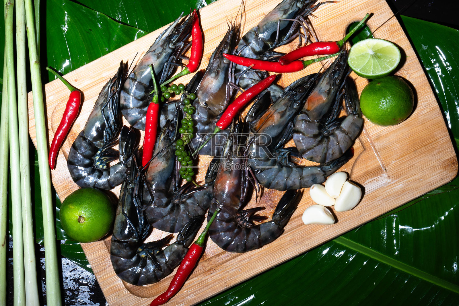 色彩斑斓的老虎虾摆放在香蕉叶上,搭配新鲜的亚洲香草和香料照片摄影图片