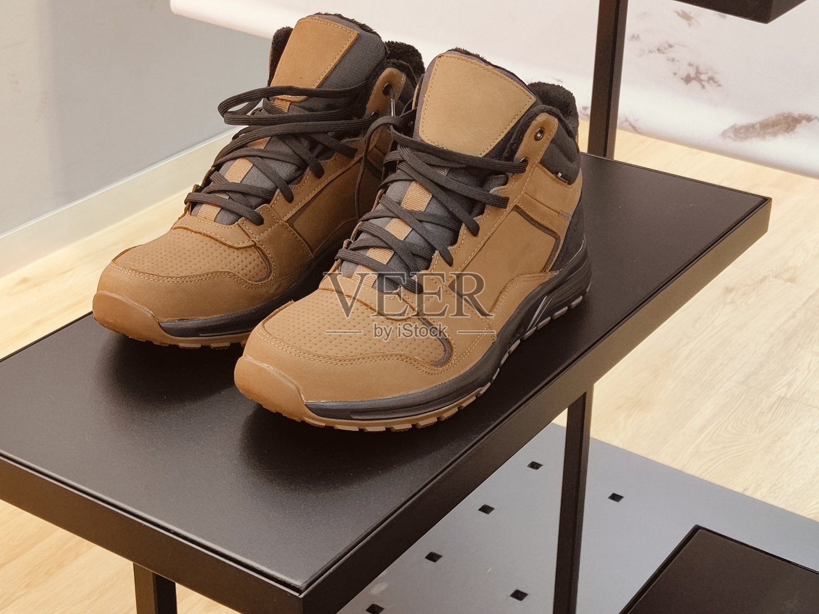 一双棕色和黑色的登山靴放在空桌子上,展示在商店里照片摄影图片