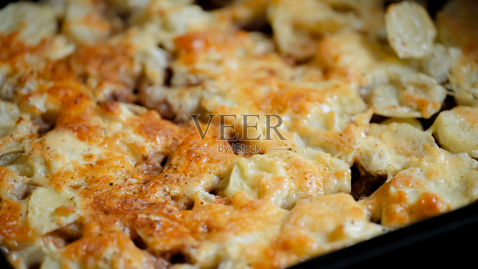 烤意大利面配融化的奶酪和金黄色的外壳,摆放在乡村风格的厨房环境中照片摄影图片