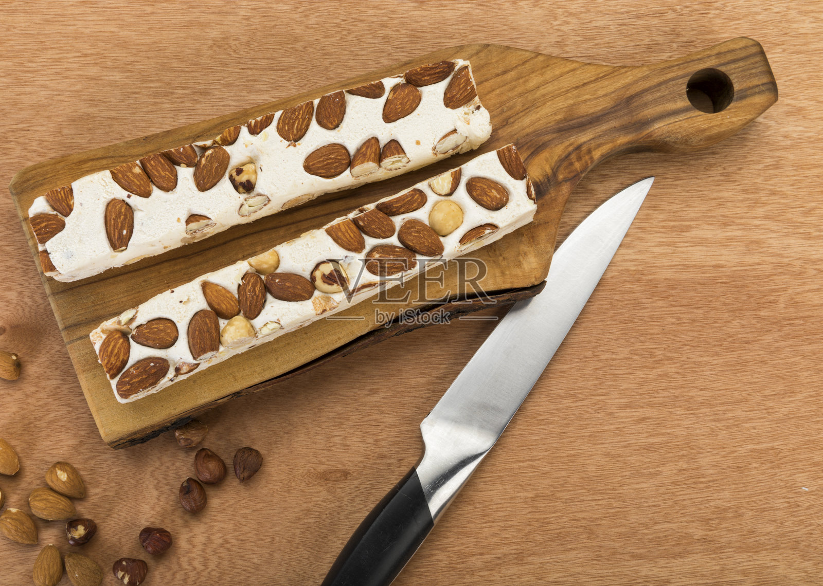 杏仁和榛子软牛轧糖块放在切菜板上,俯视角度照片摄影图片