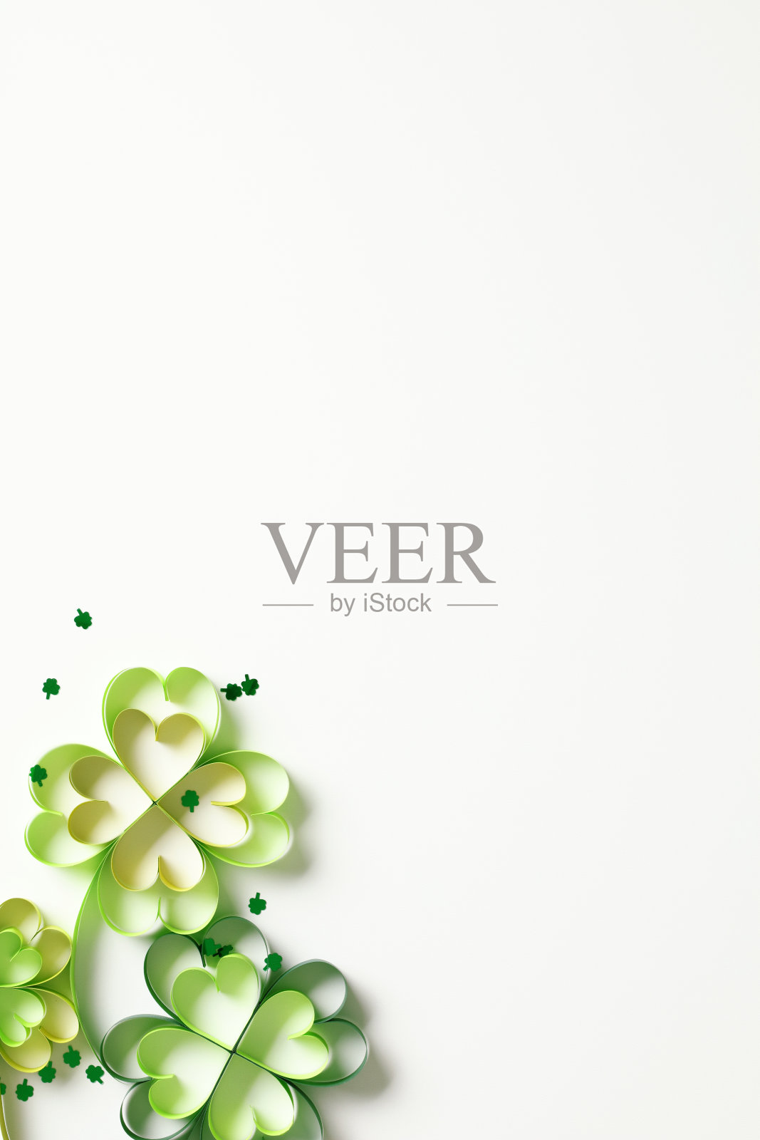 白色背景上的剪纸三叶草叶子和五彩纸屑。圣帕特里克节快乐的概念照片摄影图片