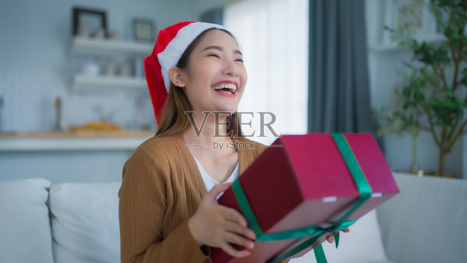 年轻的亚洲女性正在打开一个礼品盒。新年快乐,感恩节快乐,圣诞快乐照片摄影图片