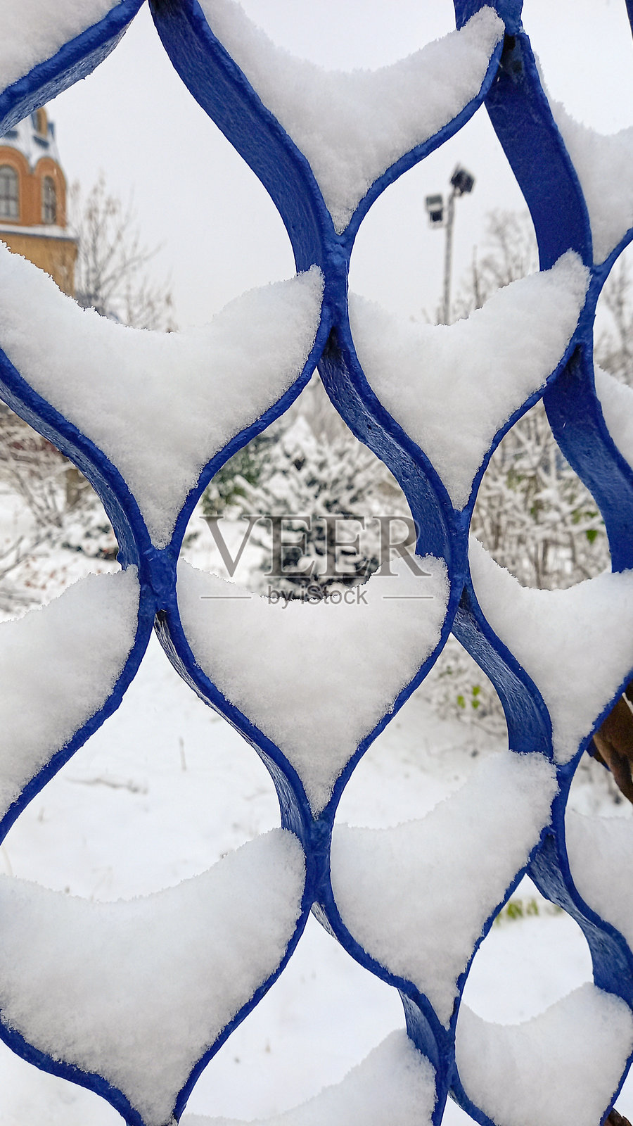 蓝色扭曲栅栏上的雪。冬天的图案。抽象艺术照片摄影图片