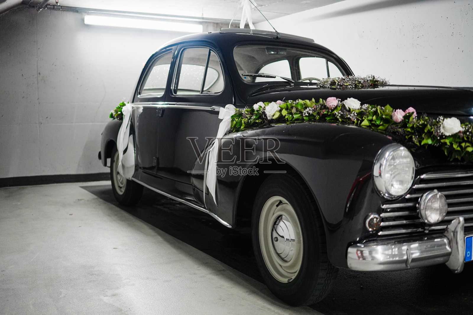 经典黑色婚车装饰着花朵,停在优雅的停车场内照片摄影图片