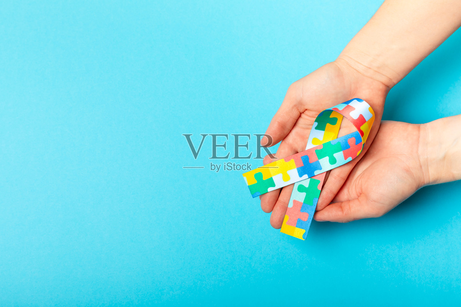 自闭症丝带。自闭症意识日。世界自闭症意识日,带有拼图图案的丝带,背景有纹理。色彩缤纷的拼图丝带。医学概念。留白空间。照片摄影图片