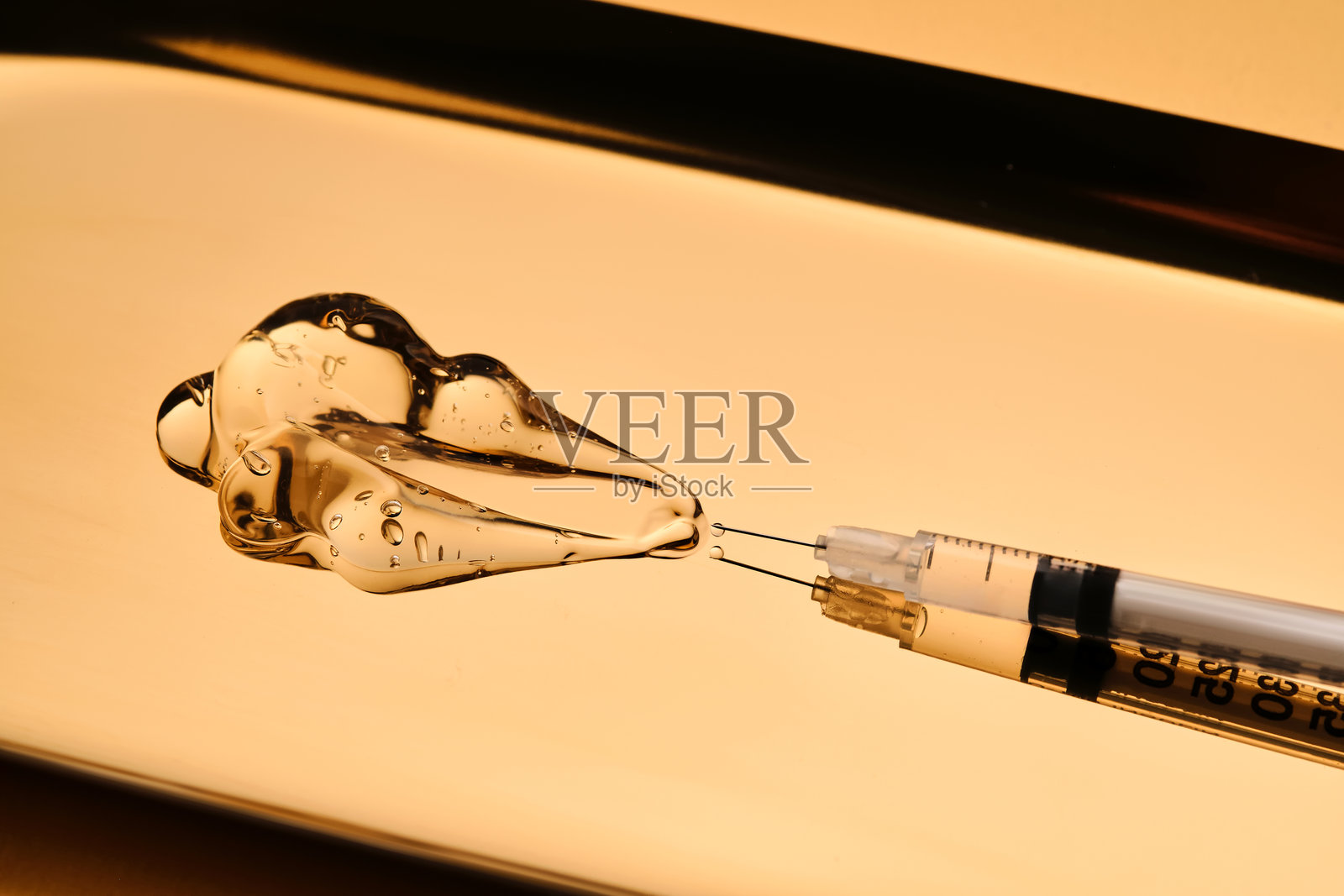 一滴凝胶从注射器中流出,用于美容程序。照片摄影图片