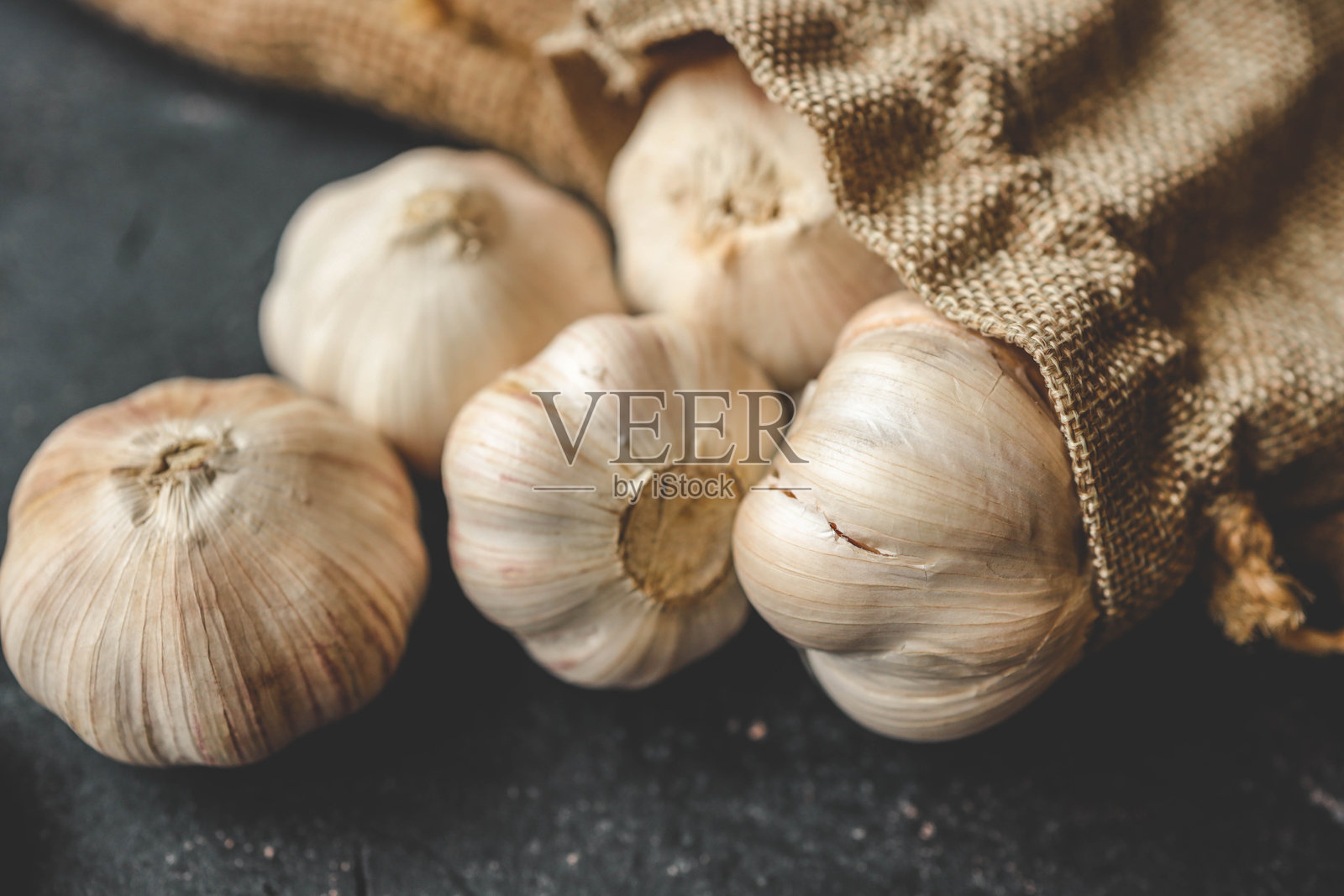 切菜板上的大蒜特写,背景为深色照片摄影图片