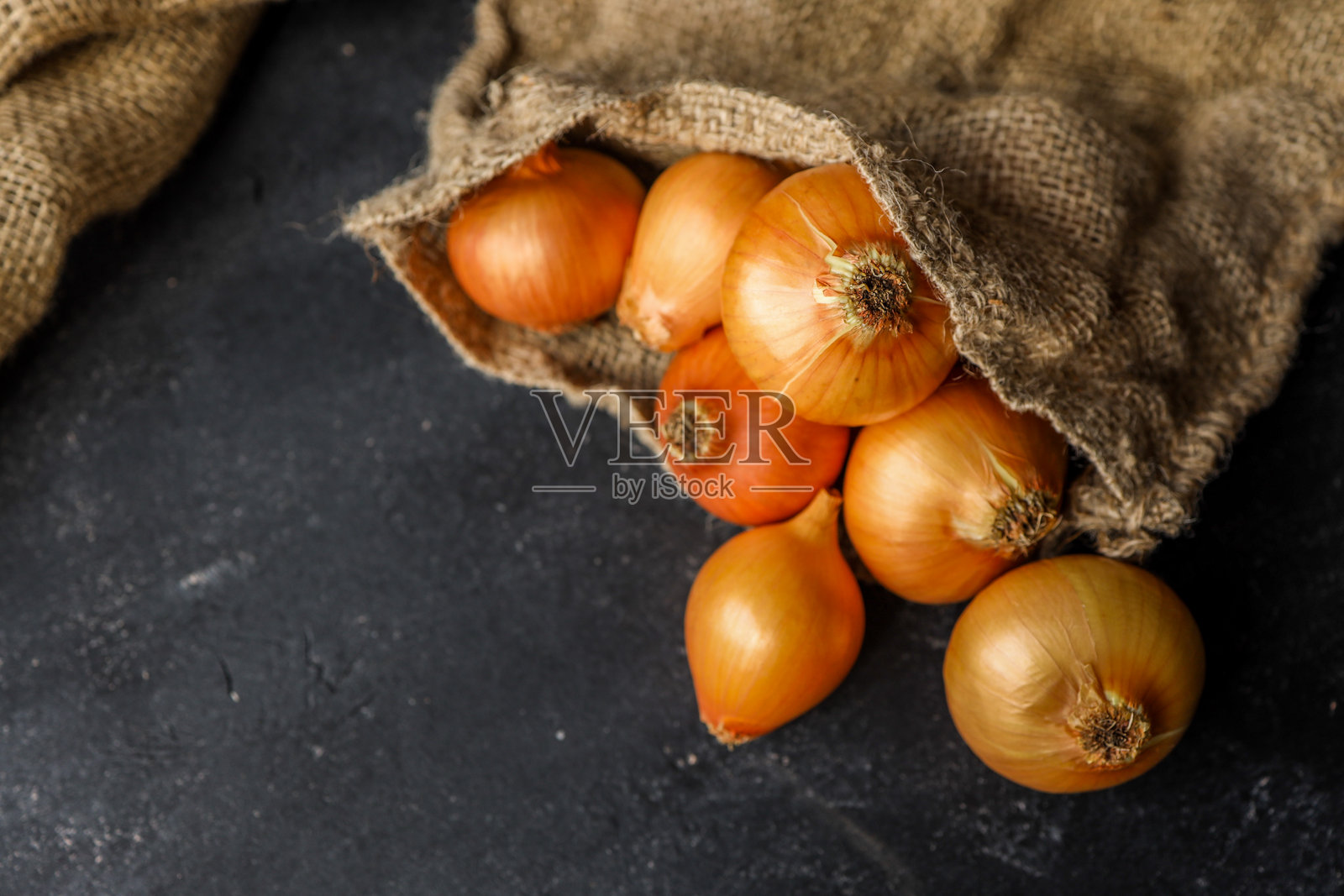 新鲜的整颗和切片的黄色洋葱放在粗糙的麻布上。非常适合有机食品、厨房准备或健康烹饪主题的概念。照片摄影图片