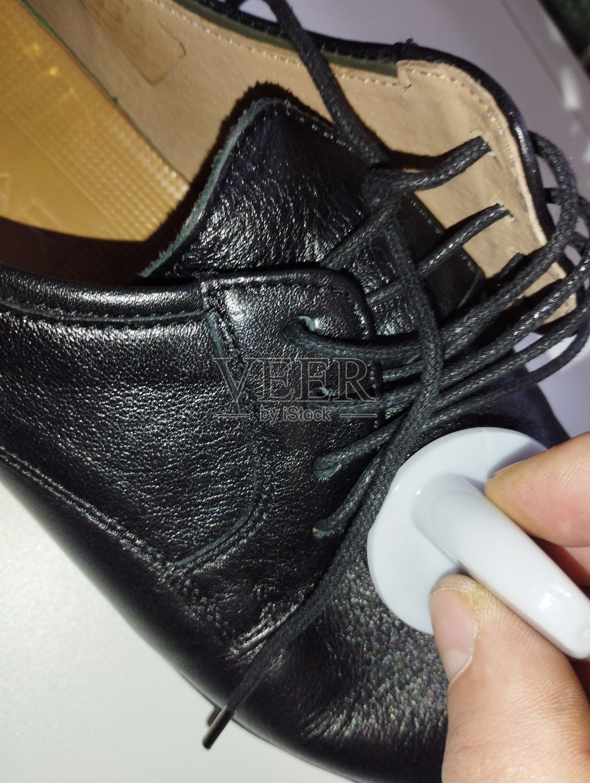 手动使用特殊柔软海绵在皮鞋表面涂抹黑色保护鞋油。照片摄影图片