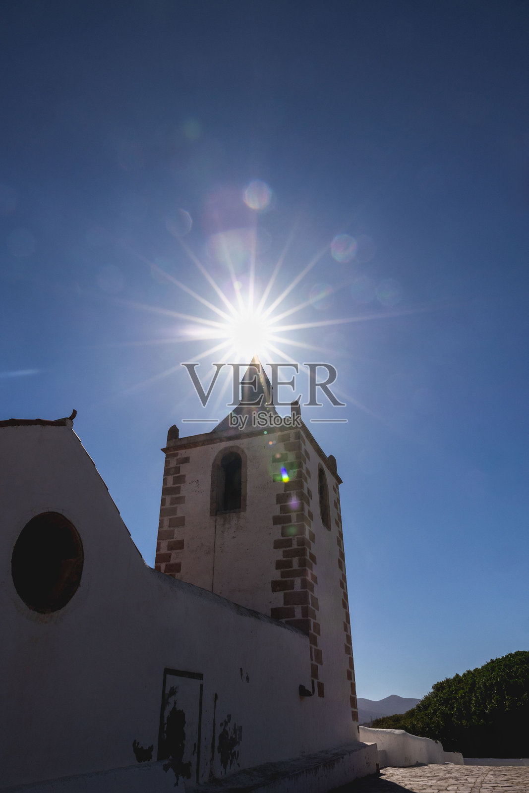 西班牙富埃特文图拉的圣玛丽亚·德·贝坦库里亚教堂塔楼的美丽景观,伴有日光辉映效果照片摄影图片