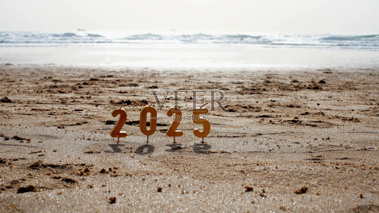 2025年新年数字形状的蜡烛在海滩上照片摄影图片