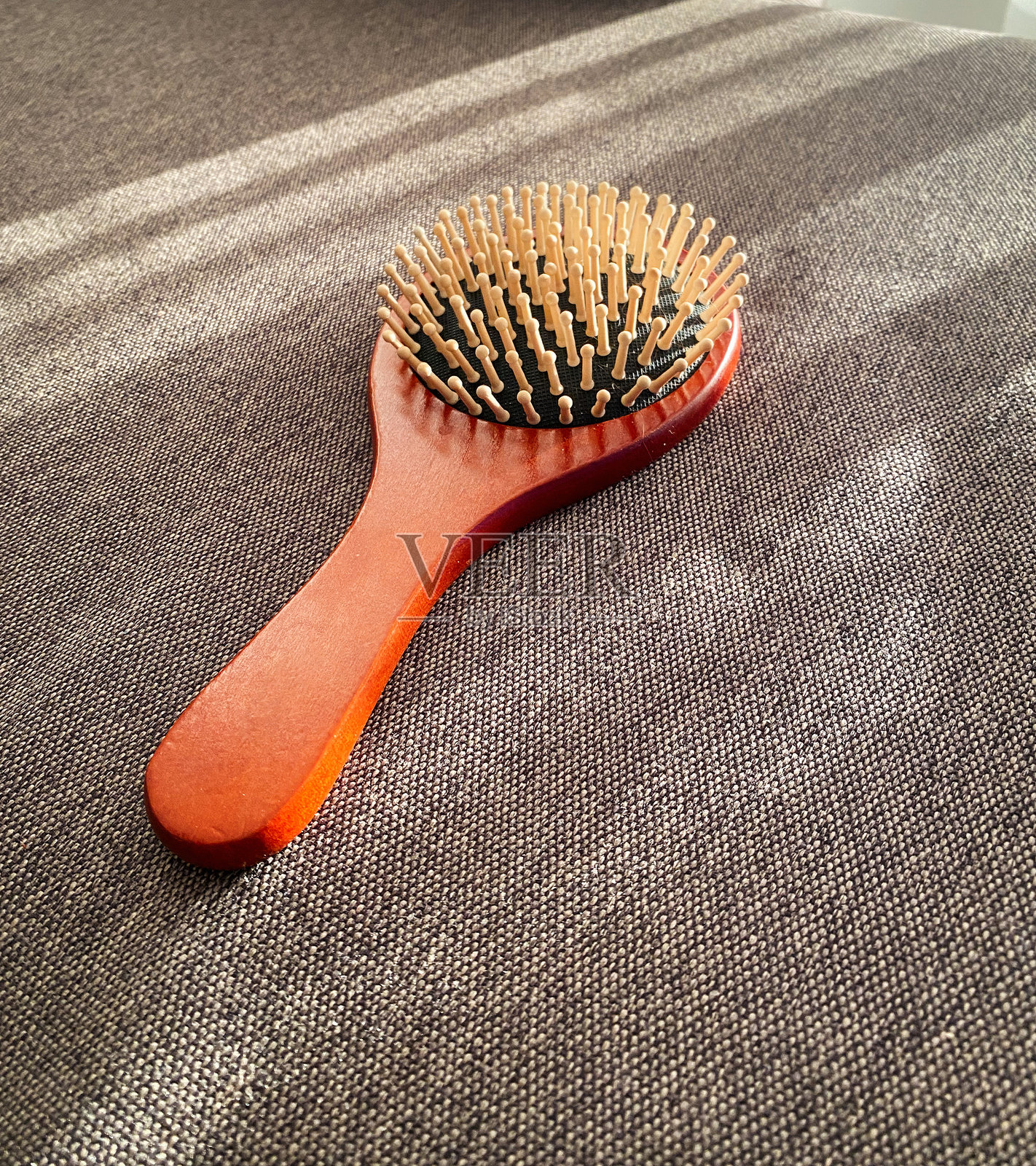 橙色梳子放在棕色布料上。照片摄影图片