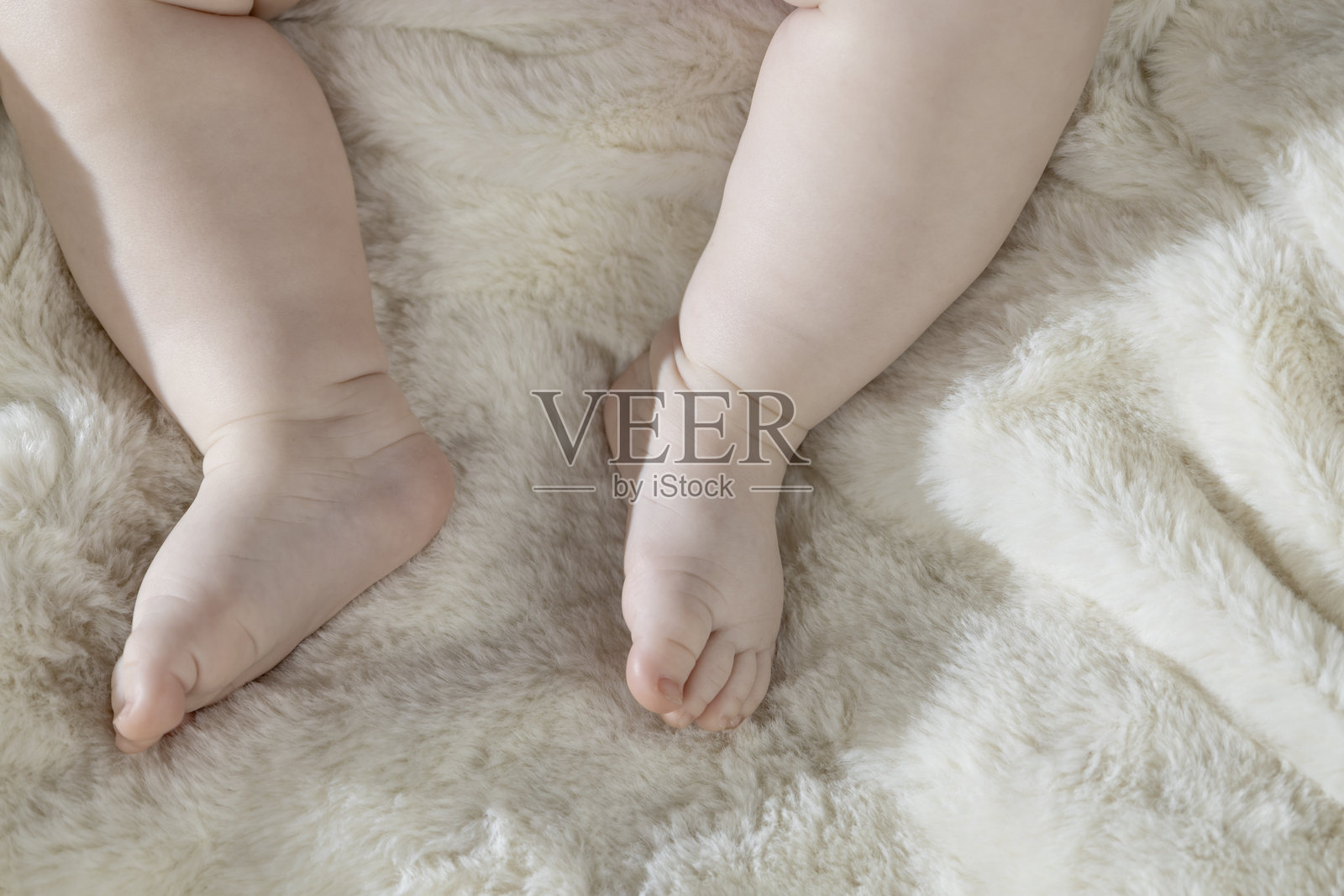 婴儿的腿躺在白色床上。照片摄影图片