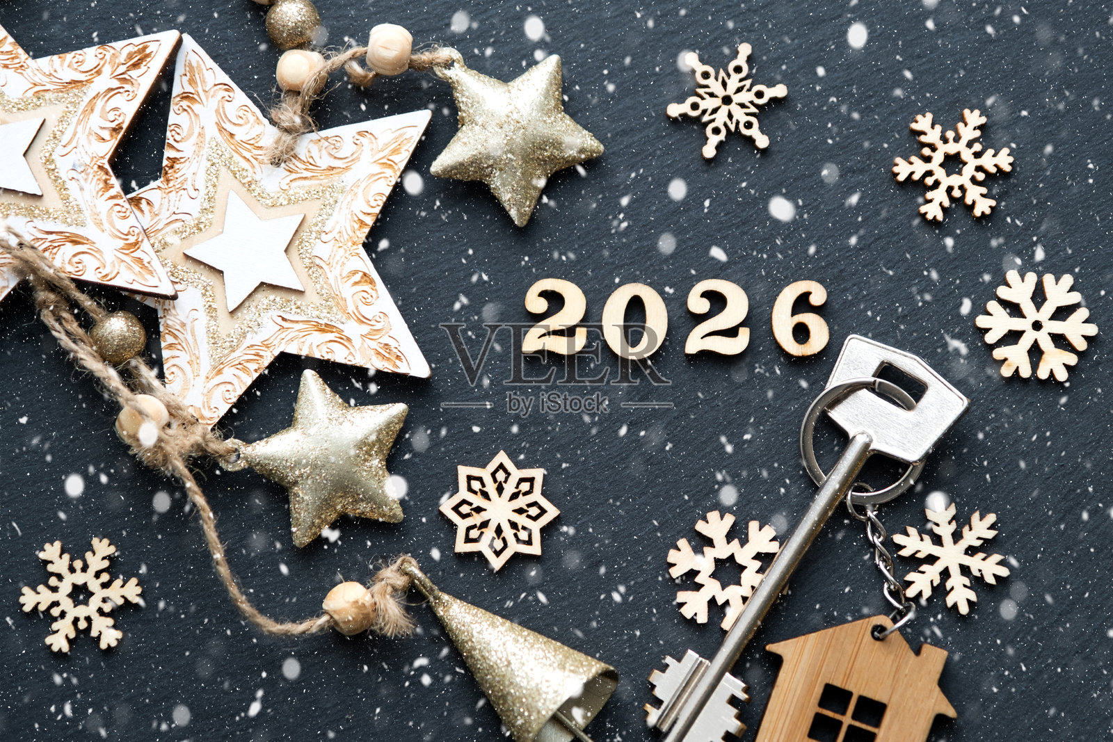 带有小屋钥匙扣的房屋钥匙,背景为节日黑色星空和灯光装饰。2026年新年木制字母,贺卡。购买、建筑、搬迁、抵押贷款、保险照片摄影图片