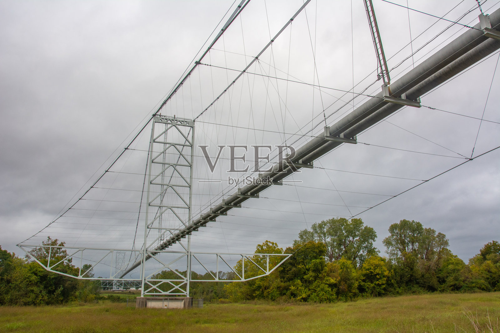 在美国阿肯色州富尔顿附近阴 gloomy 的天空下,从桥下俯瞰单跨双塔钢管悬索桥。照片摄影图片