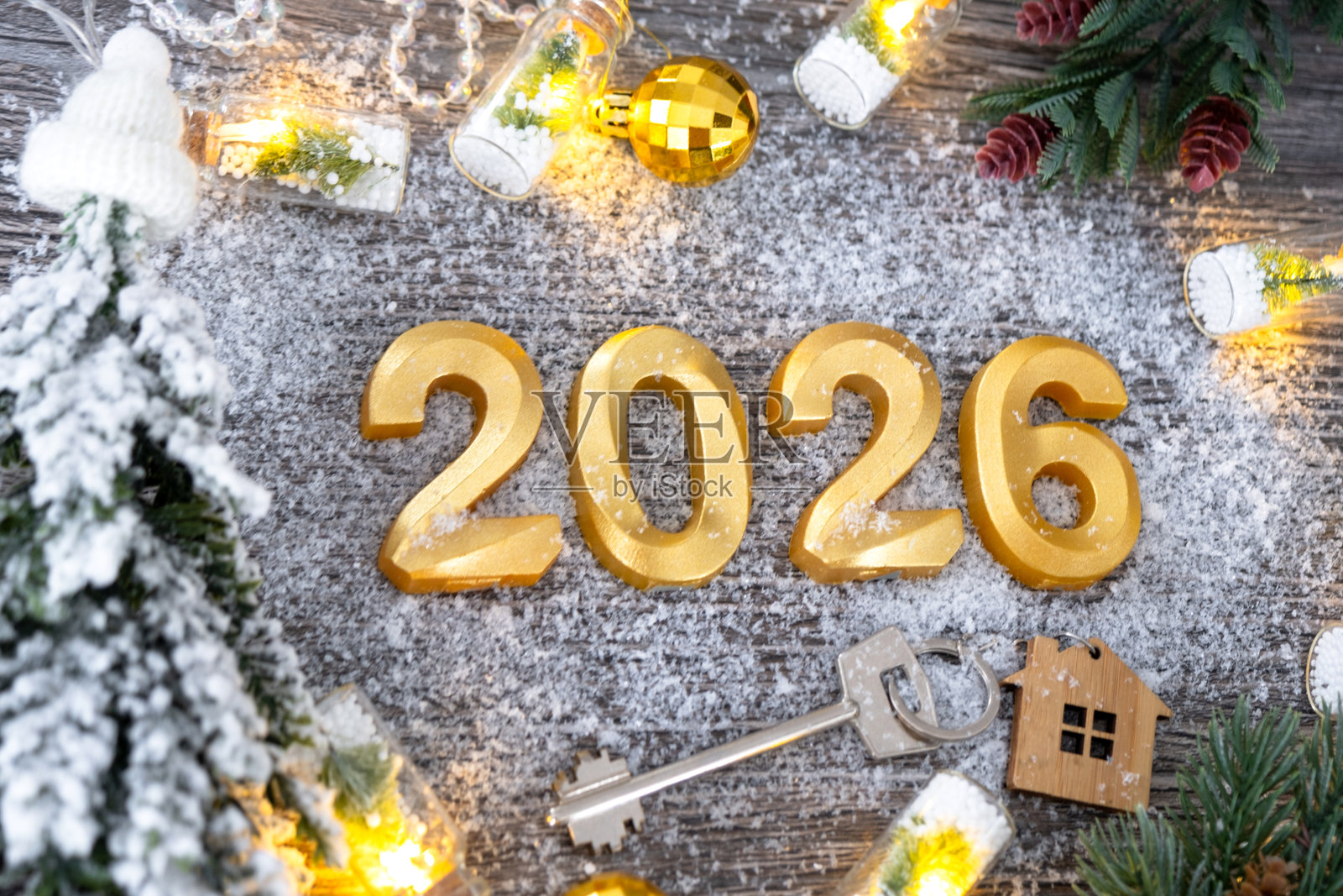 2026年新年金色数字和房屋钥匙,背景为节日灰色木纹,点缀着灯光的彩灯,贺卡。住房、房地产、搬迁、抵押贷款、保险照片摄影图片