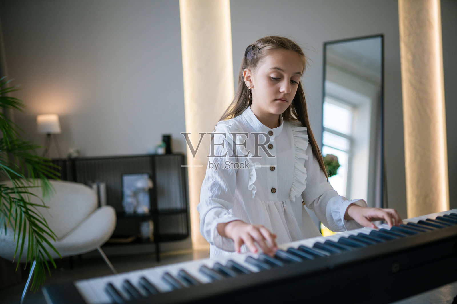 年轻女孩在客厅里弹数字钢琴照片摄影图片