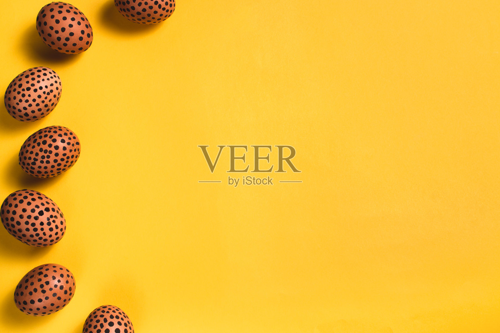 带黑点的彩绘鸡蛋。黄色表面上的复活节彩蛋俯视图。概念性的复活节平铺布局,留有空白,横向。问候卡的样板。照片摄影图片