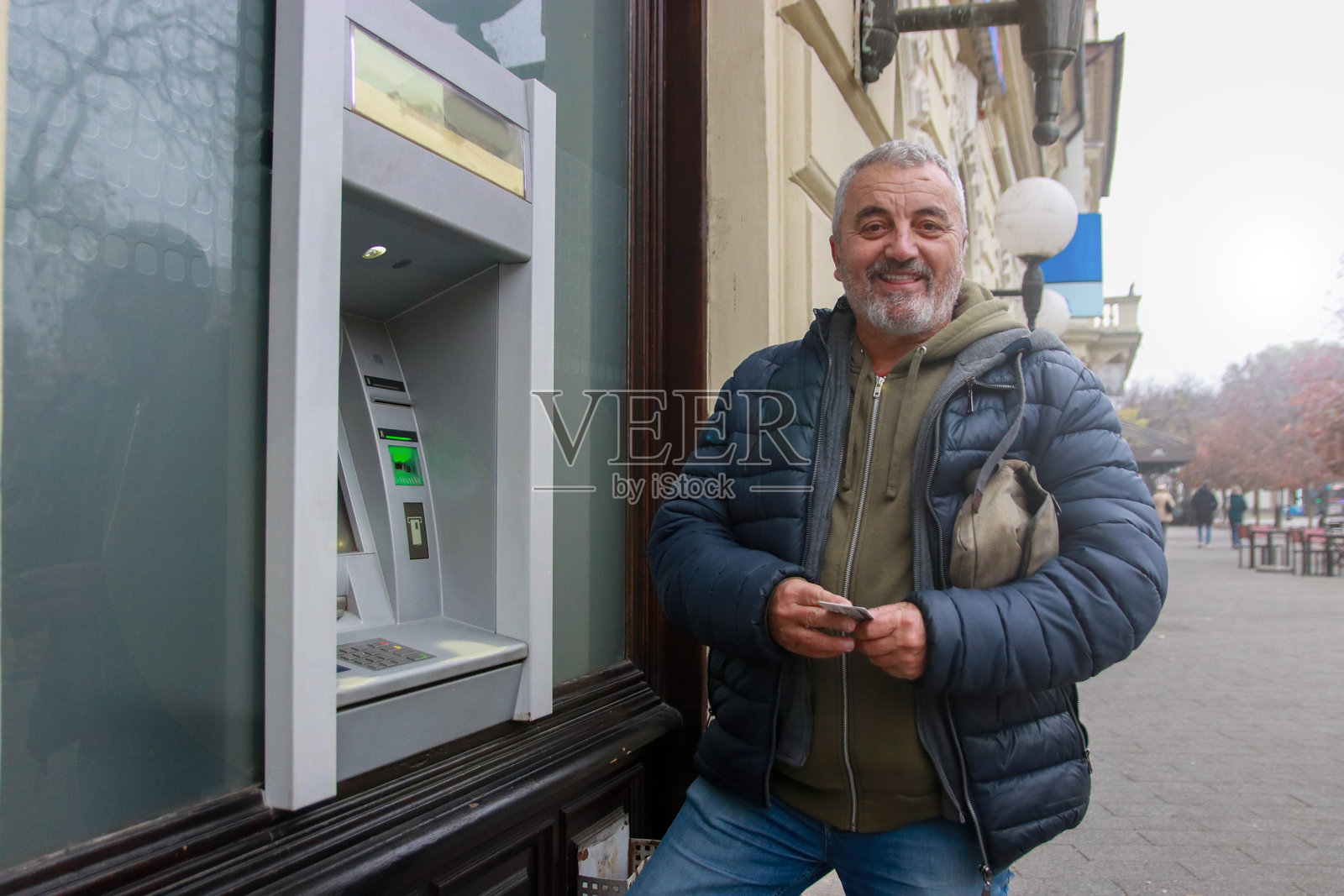 快乐的老年人正在使用自动取款机取款照片摄影图片
