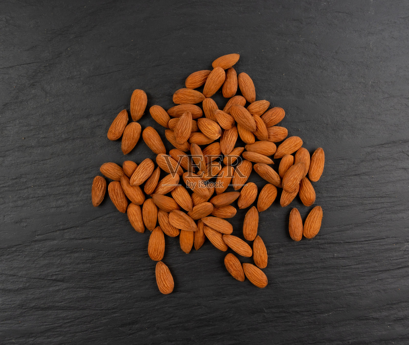杏仁堆,坚果组,完整的杏仁种子,棕色散落的果仁,黑色背景上的干生坚果照片摄影图片