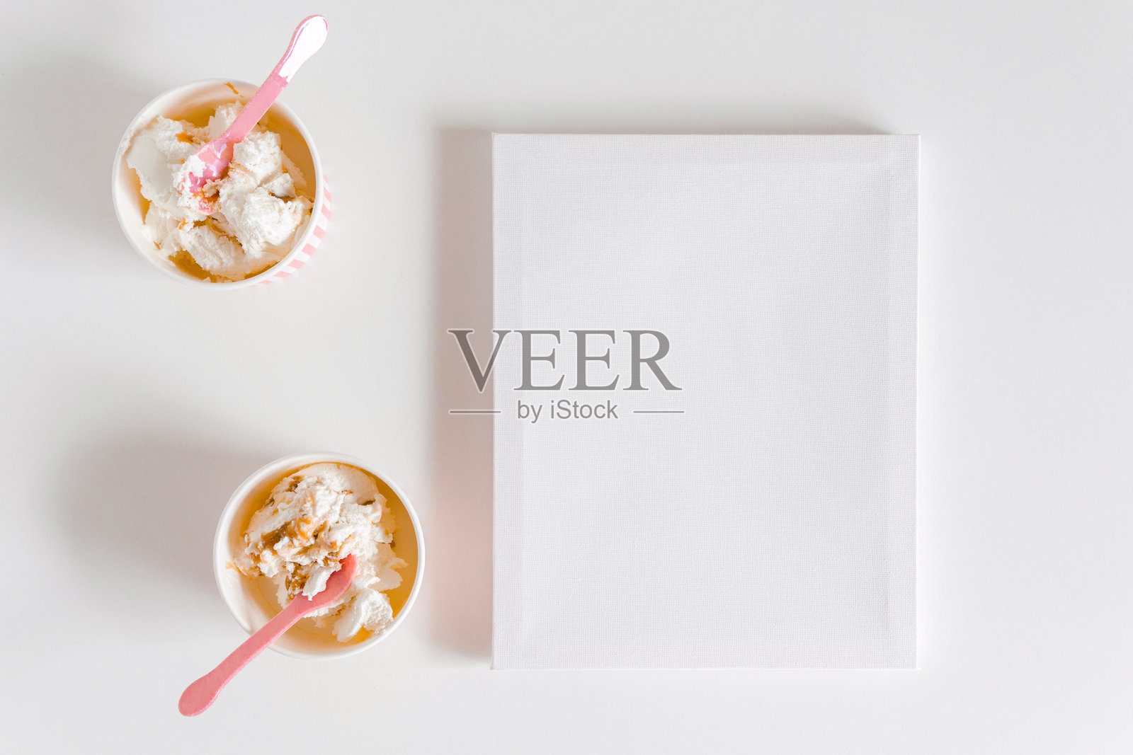 冰淇淋盒子和可爱的粉色勺子,空白画布。白色背景。设计的模型,带有空白空间的模板,平铺展示。照片摄影图片