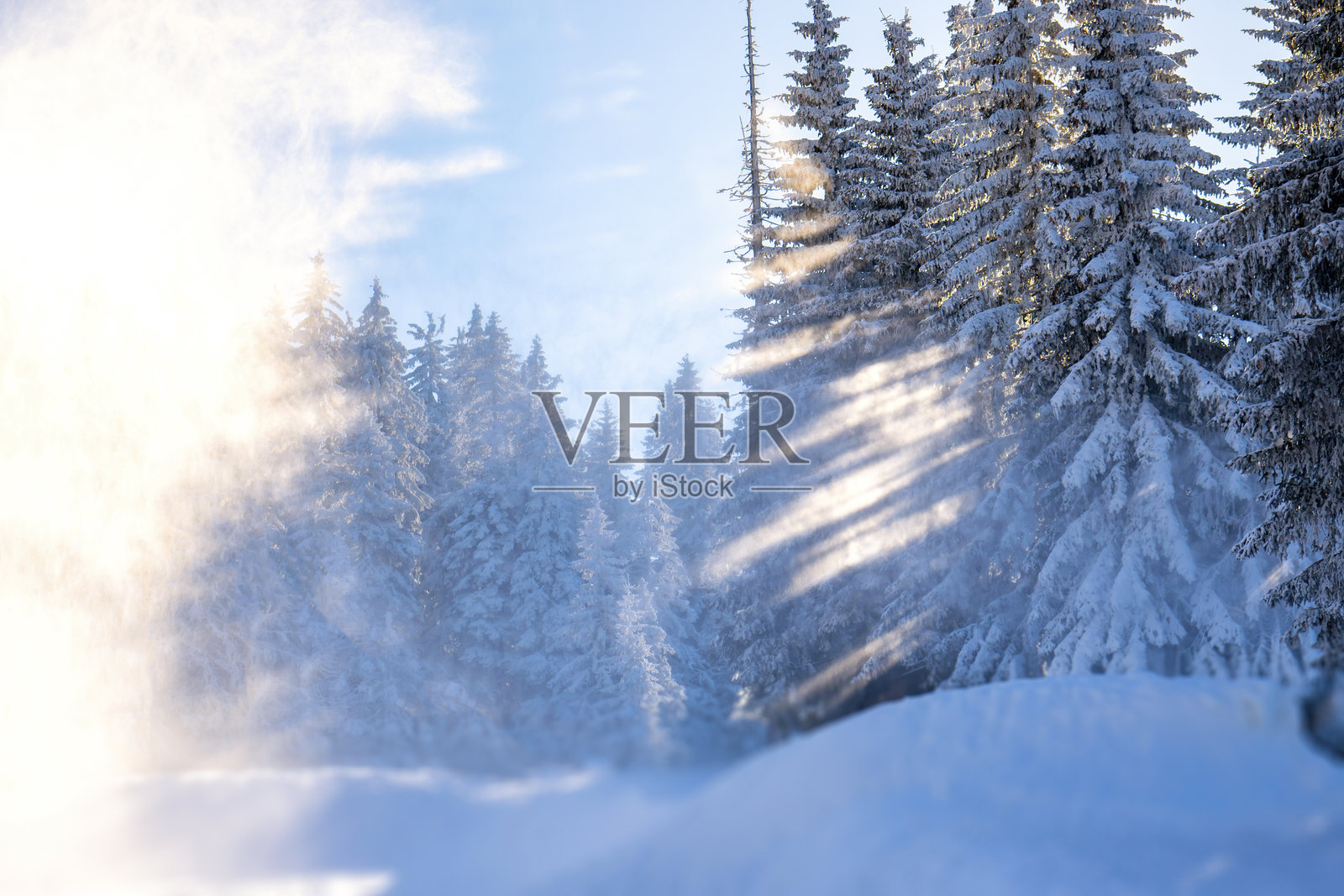 冬季田园风光,雪花飘落,阳光透射在山上。田园诗般的冬季背景照片摄影图片