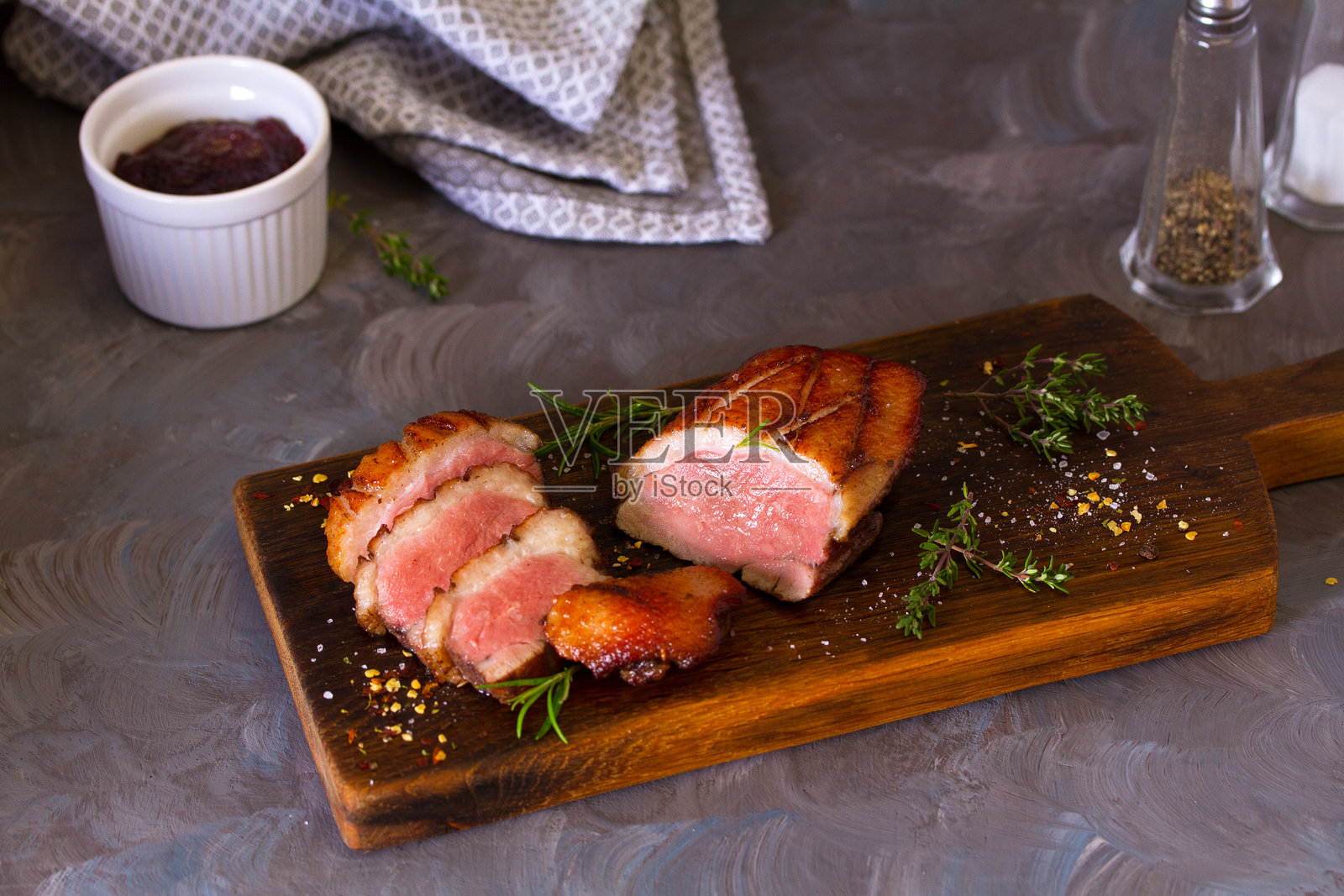 烤鸭胸肉片放在木质餐盘上,配以蔓越莓酱照片摄影图片