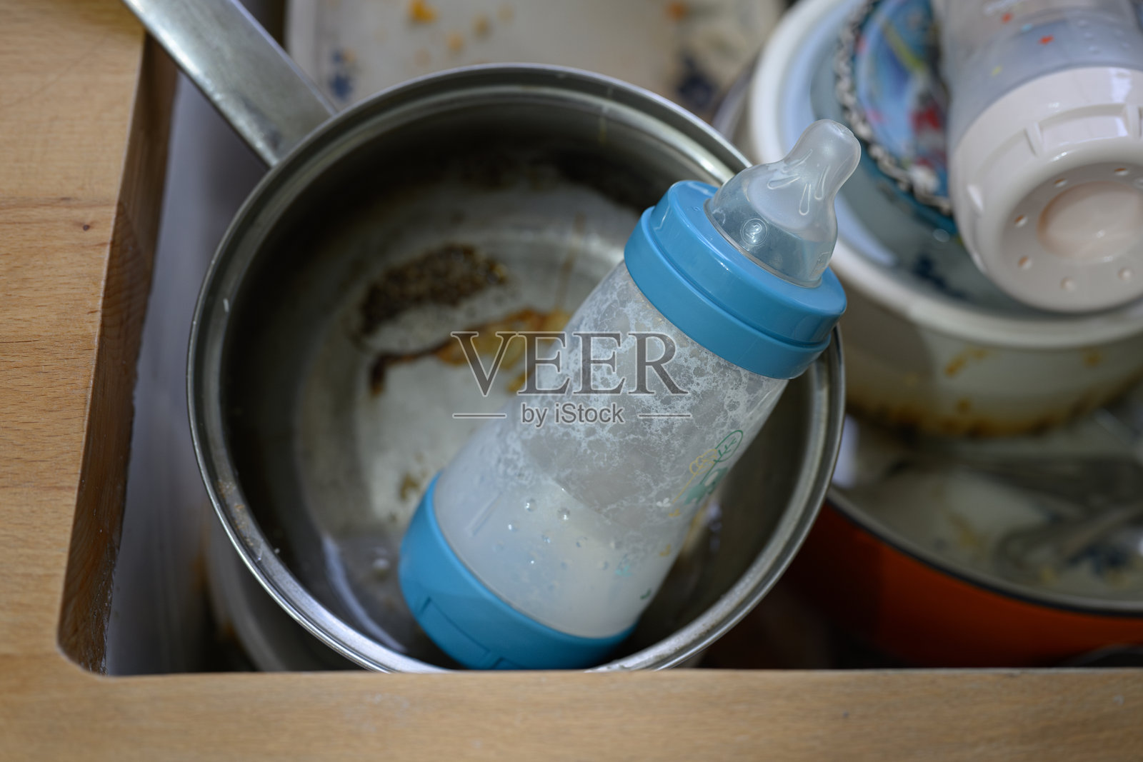 肮脏的婴儿奶瓶里有奶泡,放在肮脏的厨房水槽里照片摄影图片