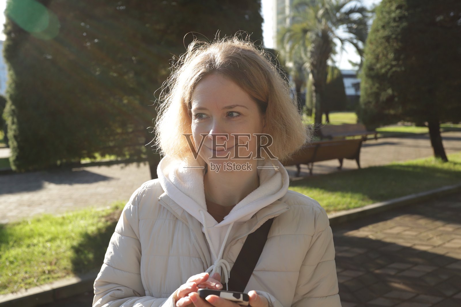 在城市公园里走路的女性,手持数字设备,利用科技在户外完成日常任务。照片摄影图片