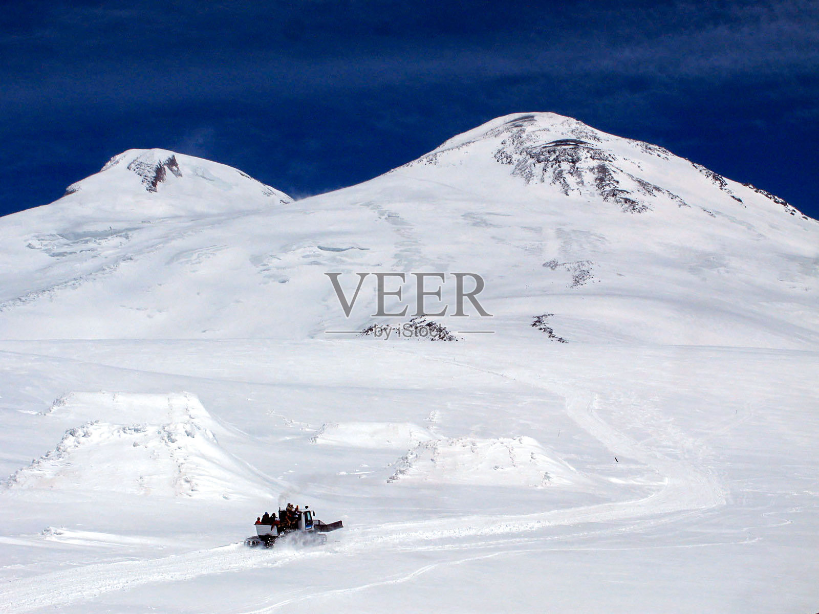 一台毛毛虫式平地机将游客运送到两座山峰之间的一个凹地,埃尔布鲁士山。照片摄影图片