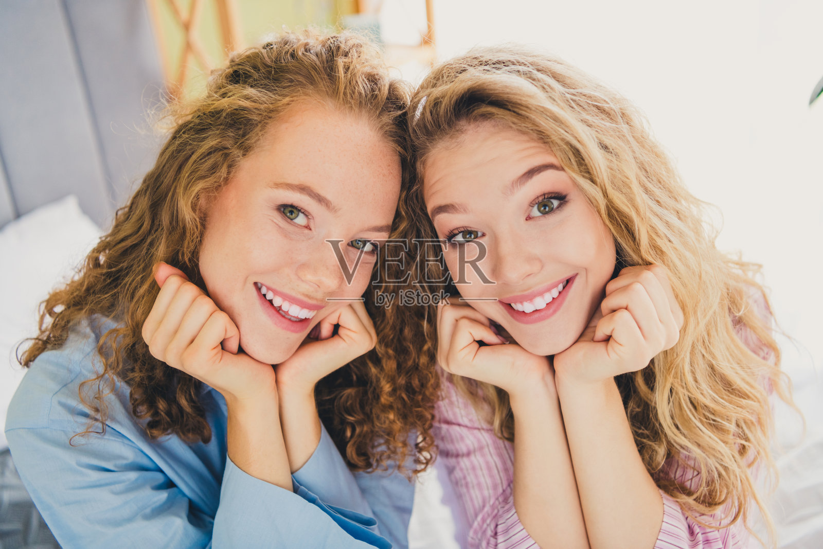 两位漂亮年轻女性在现代舒适的卧室中享受清晨的阳光,展现梦幻般的女孩气息。照片摄影图片