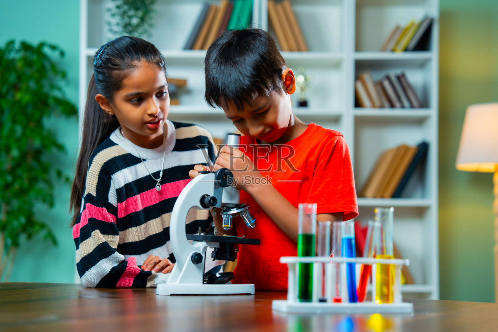 好奇的印度孩子们在学校进行有趣的科学实验,使用显微镜和试管。照片摄影图片