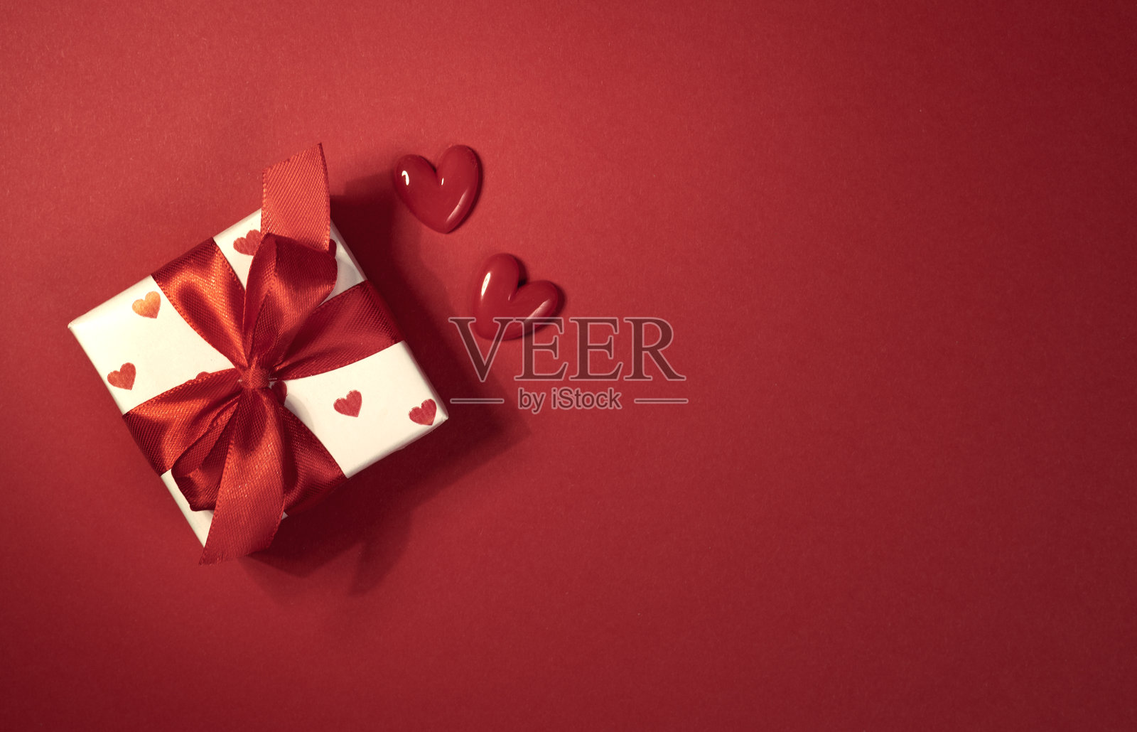 美丽的红色礼品盒俯视图,系着蝴蝶结,装饰着心形图案。情人节背景,节日空白空间背景。照片摄影图片