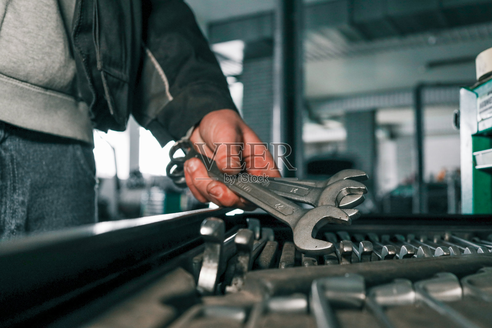 机械师的手特写,从一个井然有序的工具托盘中挑选扳手。各种尺寸的金属扳手,准备进行维修工作。照片摄影图片