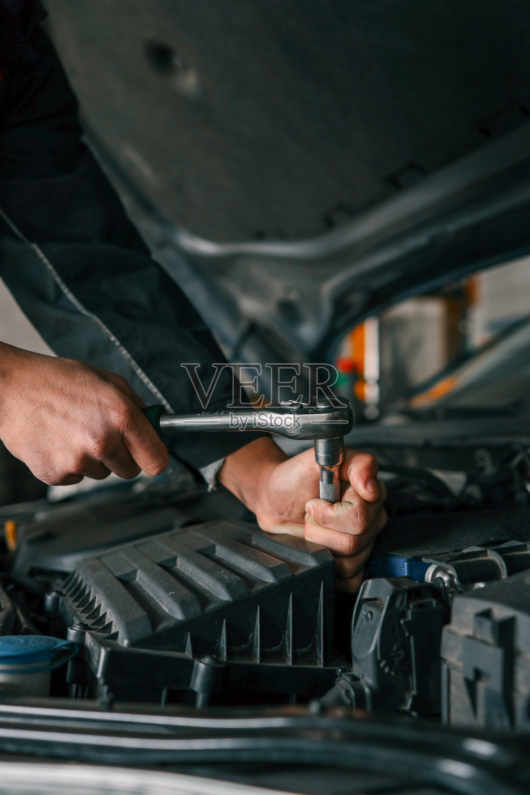 机械师在专业车间使用棘轮扳手紧固汽车发动机上的螺栓照片摄影图片